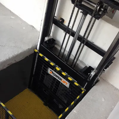 Hydraulic freight lift with visible chain drive and cargo platform